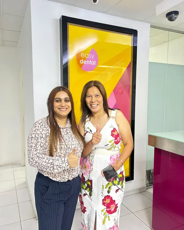 Dr Khadeeja Sulaiman with a patient in front of the Easy Dental sign
