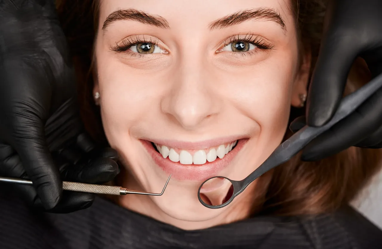 Smiling patient with dental instruments beside her mouth
