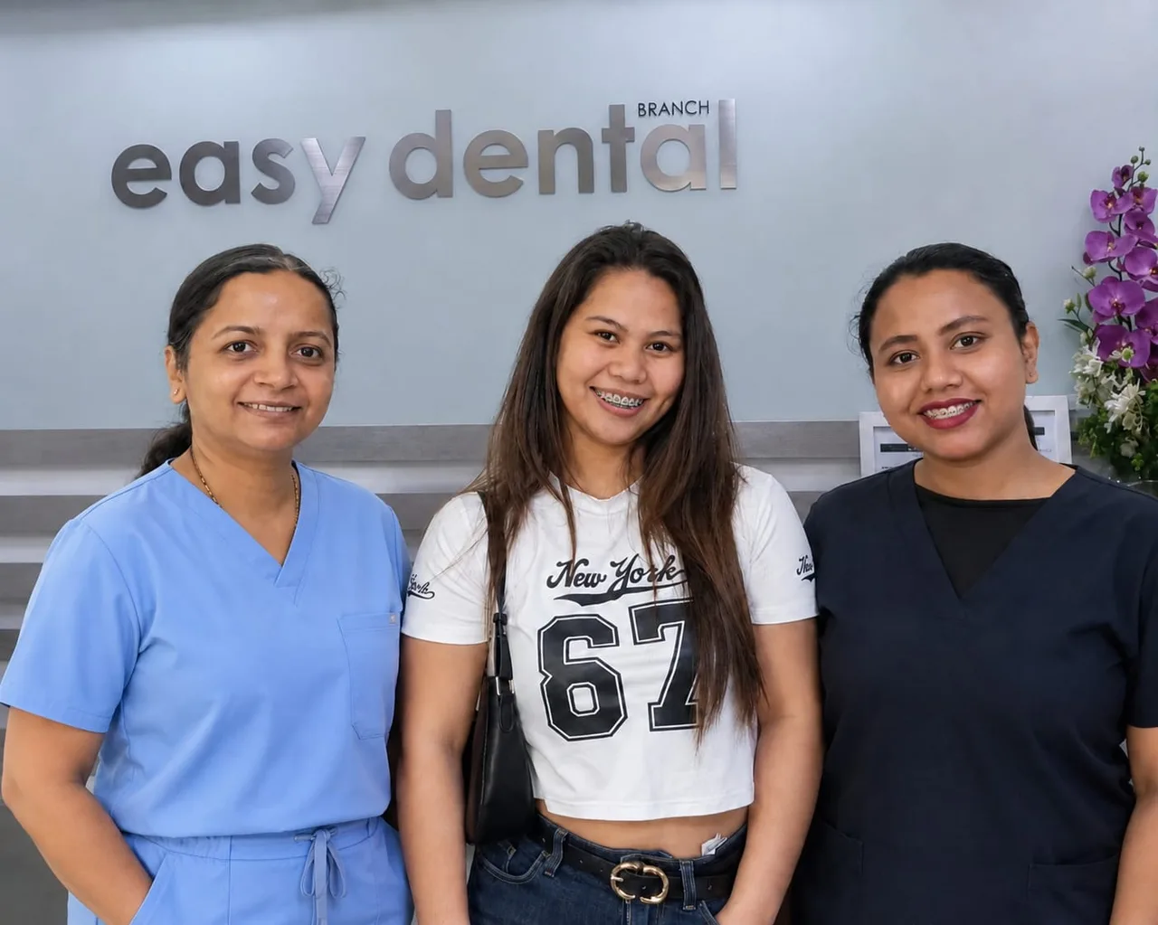 Two Easy Dental team members with a smiling patient at the Al Satwa clinic reception in Dubai