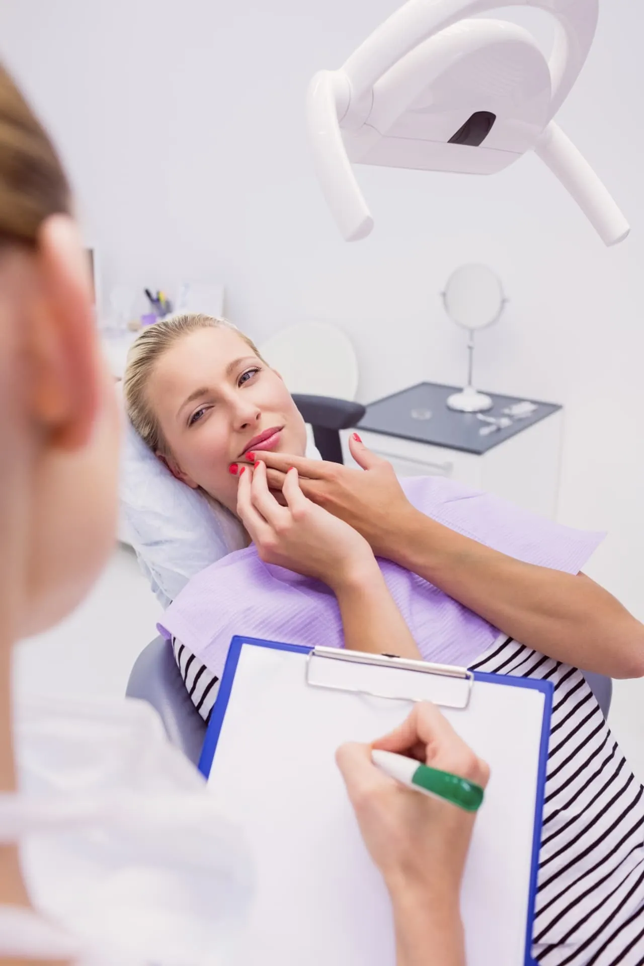Patient touching her jaw while speaking with a dentist