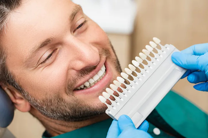 Dentist matching veneer shades against a patient's smile